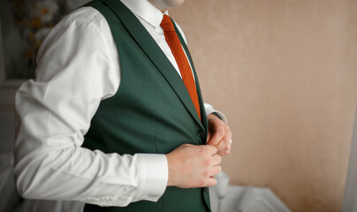The man buttons up his vest.
