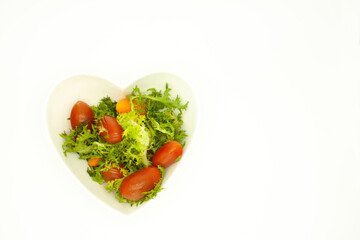 top view Mix of lettuce, carrots and red cherry tomatoes served in a ceramic heart shaped bowl