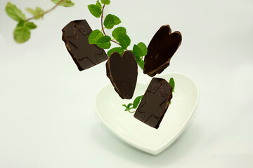 Heart and star shapes engraved on a chocolate torso that fly through the air to fall into a ceramic heart