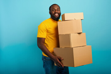 Happy man holds a lot of received packages. Cyan background
