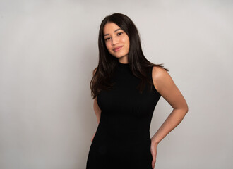 Fototapeta premium Beautiful young woman with long black hair posing in dress on grey background