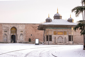 Panoramic view Fountain of Sultan Ahmed III in winter day with many snow. Imperial Gate of Topkapi...