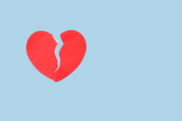 Close up red paper broken heart on blue background. Valentine's Day and depression concept