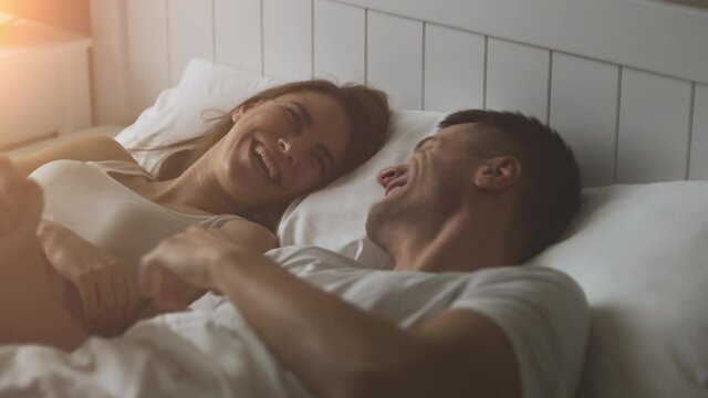 The young happy couple laughing in the bed. slow motion