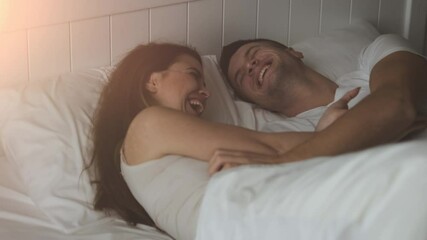 The young happy couple laughing in the bed. slow motion
