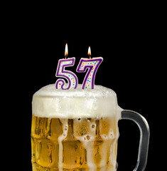 number 57 candles in beer mug for birthday celebration isolated on black 