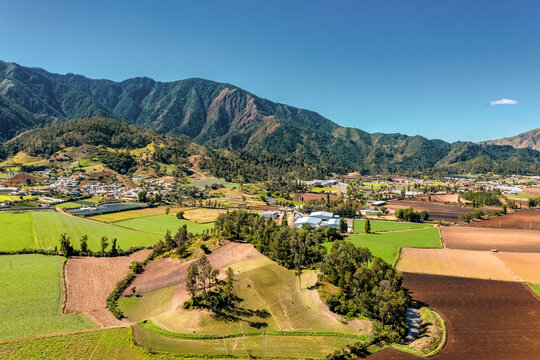 Aerial view of large mountains and agriculture under a clear sky in the constanza valley, la vega, Dominican Republic