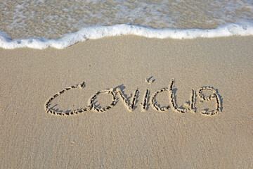 Beach sand messages : Covid-19 written in the sand on beach with wave. Concepts photography. Selective focus 