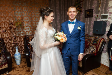 a young bride kisses and hugs the groom in the home interior, meeting the elegant lovers of the newlyweds before the wedding ceremony