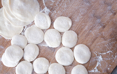 Looking down at the white dough and dumpling skin on the chopping board