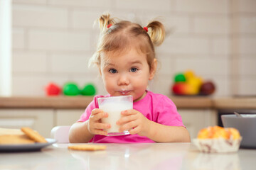 happy baby sitting at the table in the kitchen and eating with an appetite