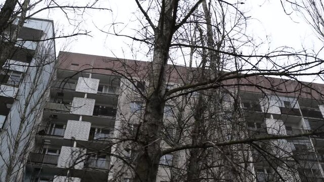 Pan over Prypyat desolate apartment buildings in chernobyl exclusion zone in 2020 after reactor tragedy. Foggy weather and dark light.