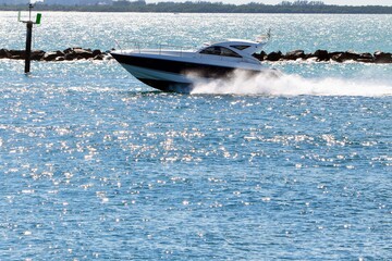 Cabin cruiser racing through Government Cut,Miami Beach,Florida on its way to open ocean.