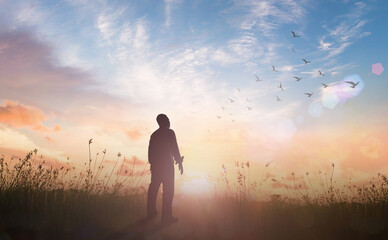 World mental health day concept: Silhouette of human standing to worship God in meadow autumn sunset background