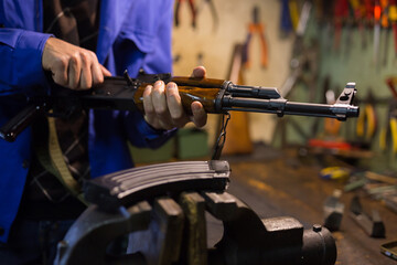 Closeup of Kalashnikov assault rifle in hands of gunsmith. Professional firearms maintenance concept