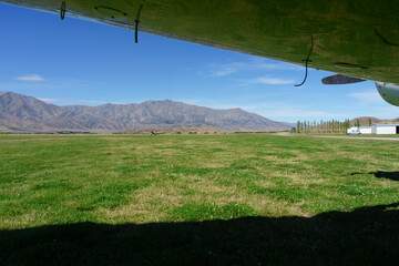 Scenic mountains framed by plane wing and shadow - obrazy, fototapety, plakaty