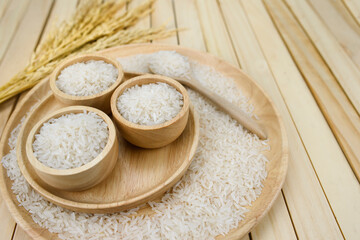 jasmine rice in a bowl on dark wooden table with rice plants, ear of rices with jasmine rice in a bowl , rice scatter on the floor.