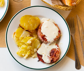 Appetizing roasted turkey breast steaks with Roquefort cheese sauce served with fried potato with onion.