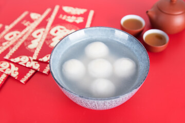 A bowl of lantern festival dumplings or Lantern Festival red envelopes and traditional tea on the red background