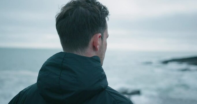 Caucasian man standing at the shore and looking into the distance