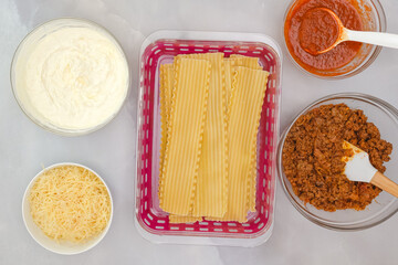 Boiled lasagna noodles, marinara sauce, ground beef, cheese in bowls. Ingredients for beef lasagna...