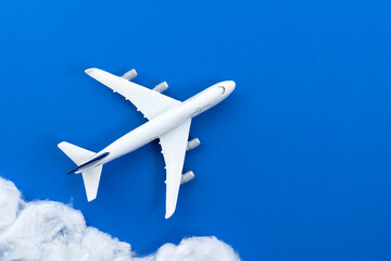 Commercial airplane model flying among cotton clouds for traveling and aviation industry concept