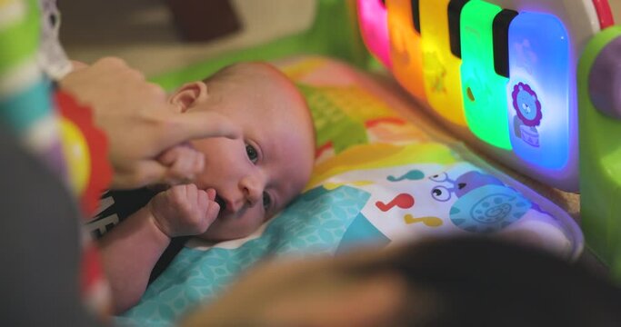 Baby staring at mother while laying on playmat