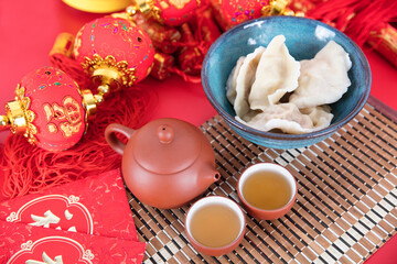 A bowl of white dumplings and exquisite tea on a red background