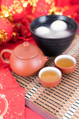 A bowl of glutinous rice balls, tea and red envelopes on the background of festivity