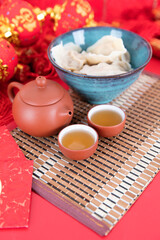 A bowl of white dumplings and exquisite tea on a red background