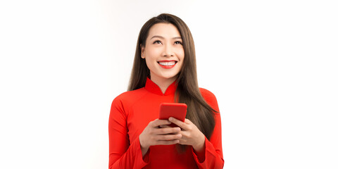 Image of happy young woman in vietnamese traditional dress chatting by phone standing isolated over white. Looking aside.