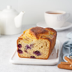Banana bread, sliced cake with banana and blueberries. Morning breakfast with tea on light gray cincrete background