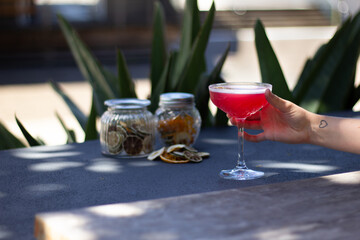 Cosmopolitan Red Cocktail in a coupe outside in garden with hand. Great on it's own, for social media or for a poster.