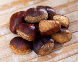 Pile of unpeeled sweet chestnuts on wooden table