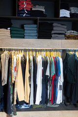 Men clothing shop, variety of casual clothes on hangers and shelves in garments store