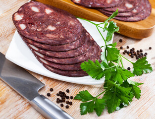 Close up of Spanish smoked blood sausage on white plate on wooden table