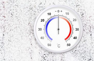 Naklejka premium Celsius scale thermometer on a frozen window shows zero degrees