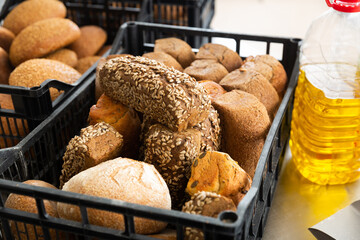 Freshly baked hot bread in plastic crate on table with ingredients, industrial bread production