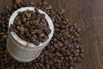 Coffee beans in small wooden bucket with coffee beans on table