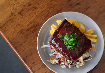 BBQ Pork Ribs on wooden table with fries and slaw. Great on it's own, for social media or for a poster.
