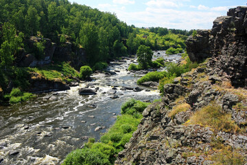 A fast mountain river flows between green banks