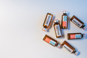 Ampules of different coronavirus vaccine lie randomly on white lab table, close-up. Covid-19 background with copy space. Development of antiviral drug. Mass vaccination of population concept.