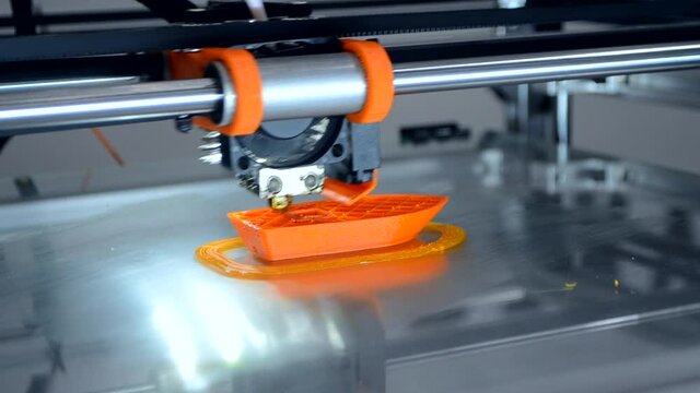 3d printer prints orange object model orange color close-up.