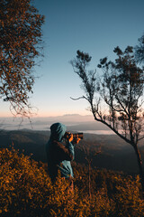 The photographer is taking pictures of the forest and mountains in the morning.