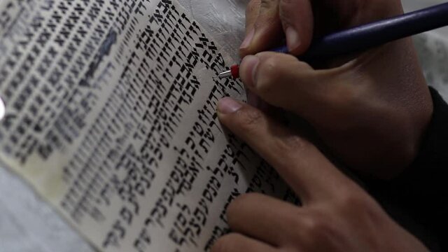 A writer's hand practices decorating letters from a Torah scroll written on parchment in Hebrew, (for the editor - the Hebrew letters are random without meaning)