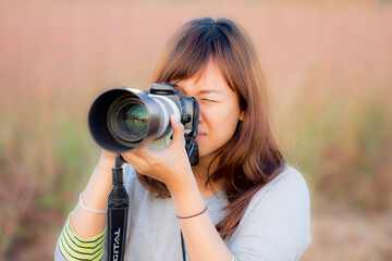 Portrait of photographer covering her face with the camera, Happy woman on vacation photographing with a dslr