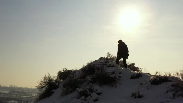 The person reaches the  height in winter and look around. In background small town and bridge. Motivation footage.
