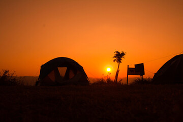 Fototapeta na wymiar Silhouette on sunrise, a group of tourists or adventurers with tent, travel to nature.