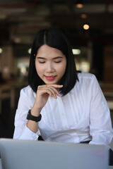 Portrait of young female office worker working on laptop computer in the office.