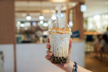 Brown Sugar Bubble Fresh Milk. Woman holding a plastic cup of fresh milk with brown sugar sauce and...